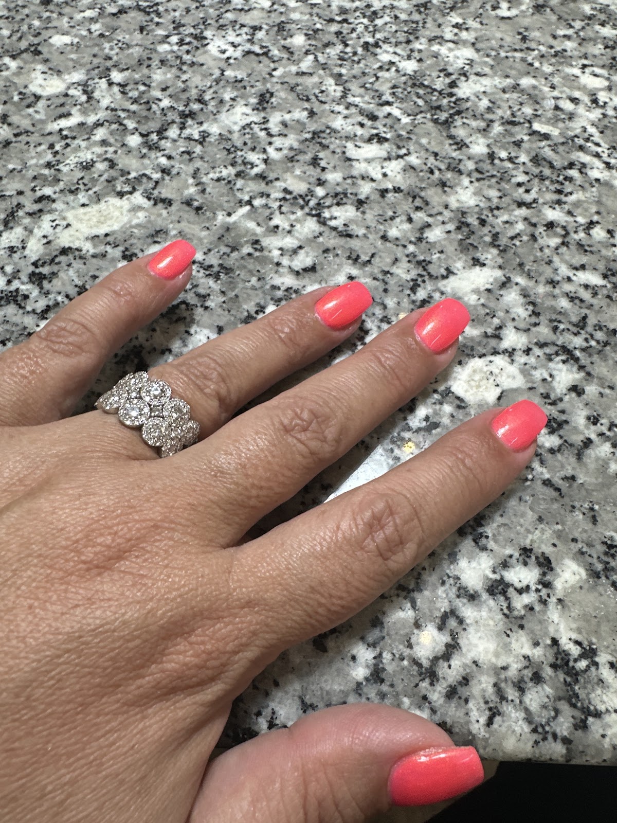 Bright coral polish on a client's hand