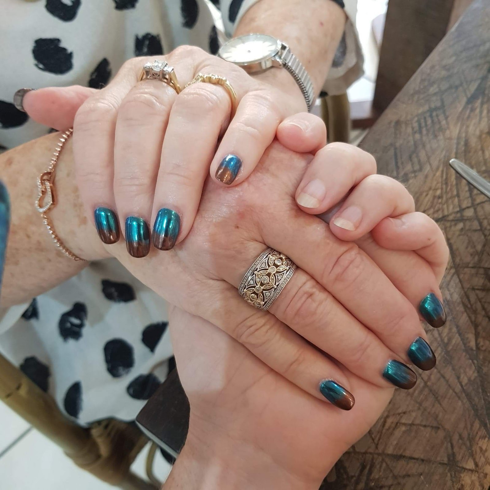 Teal chrome nails on two clients holding hands